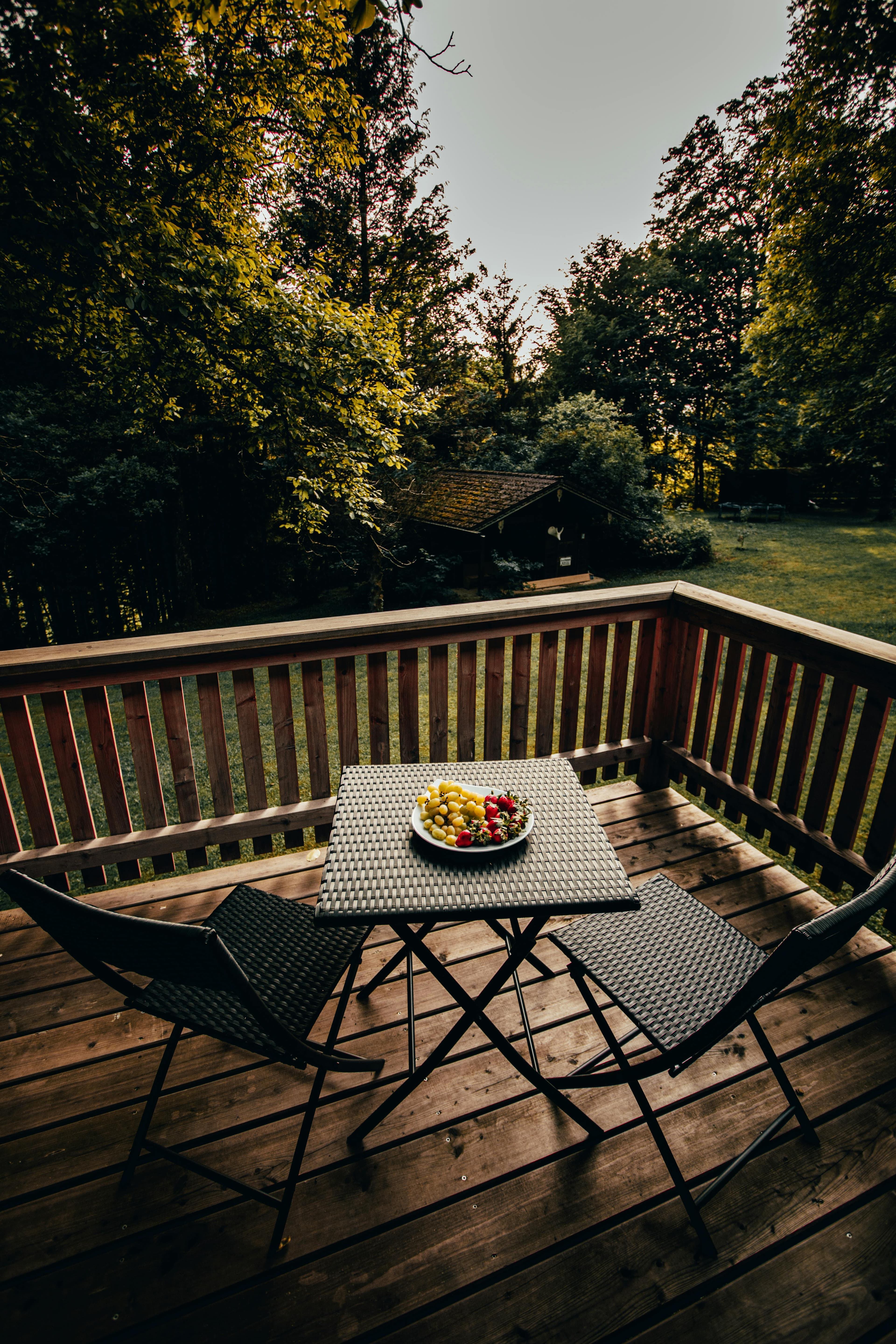 Handyman staining a backyard deck on a sunny afternoon