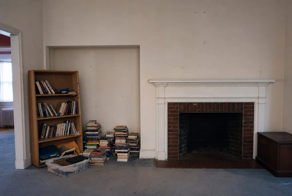 Empty fireplace alcove with cluttered shelf before built-ins